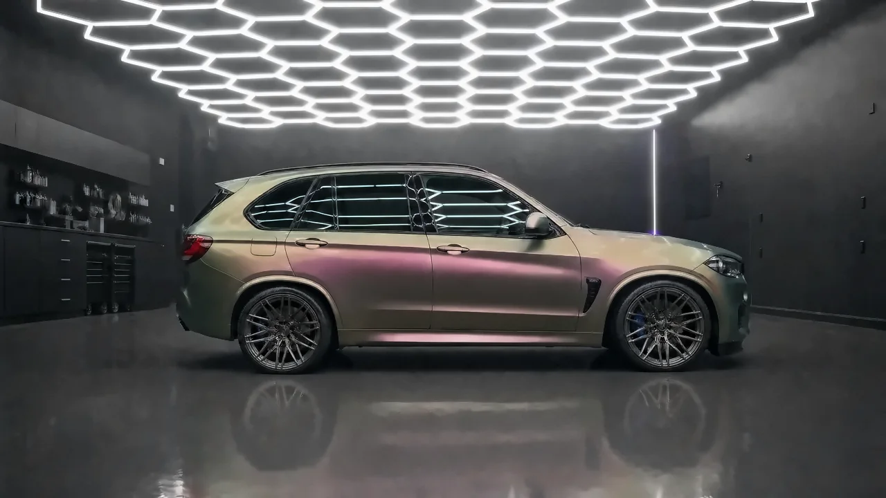 BMW X5 M in a color-shift wrap that turns green, gold and violet (studio illustration)