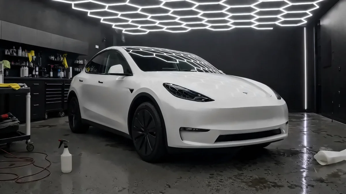 White Tesla Model Y-style crossover in factory paint, before any film (studio illustration)